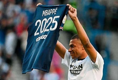 Paris Saint-Germain's French striker Kylian Mbappe poses in a shirt after announcing that he will stay at Paris Saint-Germain until 2025 ahead of the French L1 football match between Paris Saint-Germain (PSG) and Metz at the Parc des Princes stadium in Paris on May 21, 2022 (Photo by Anne-Christine Bogolat/AFP)