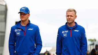 Mick Schumacher and Kevin Magnussen walk in the field.