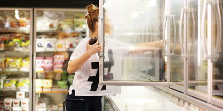 A woman picks out frozen foods from the freezer in the supermarket