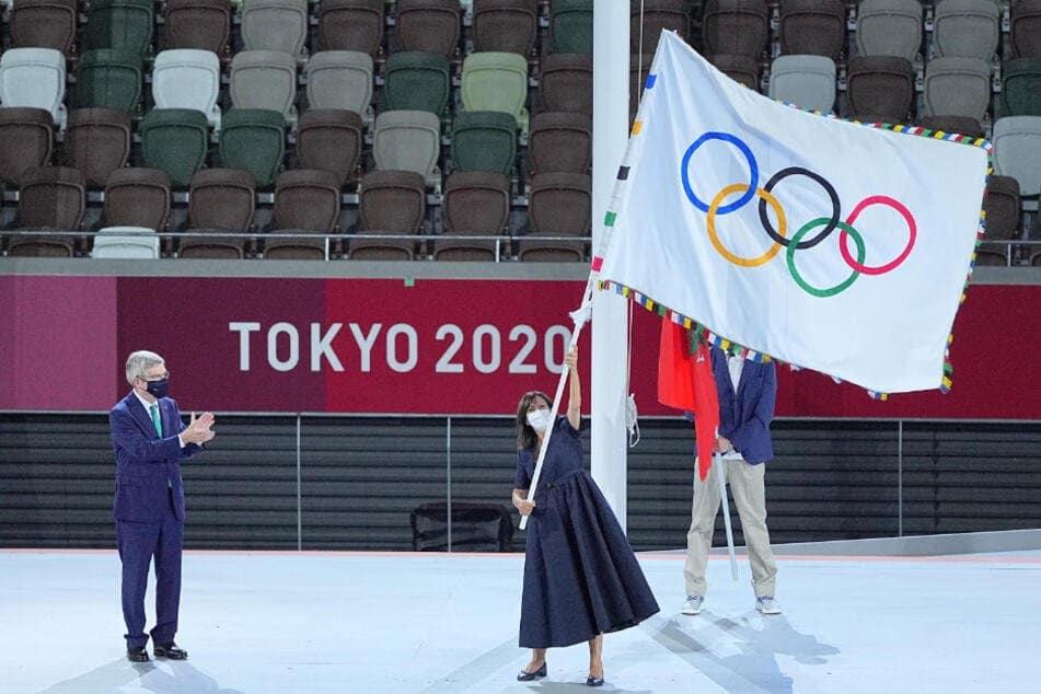 Anne Hidalgo (62, center), mayor of Paris, waves the Olympic flag.