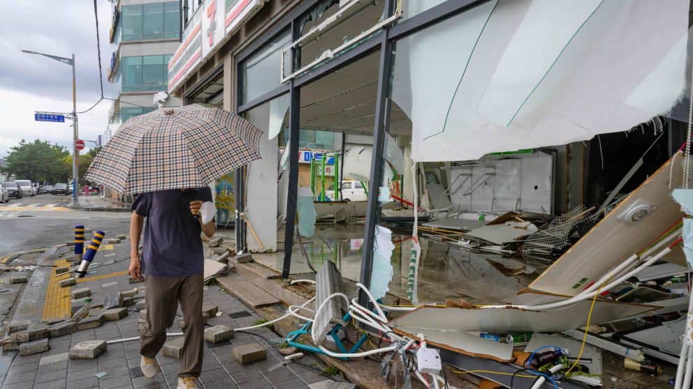 A man walks past a tornado-damaged building in Busan