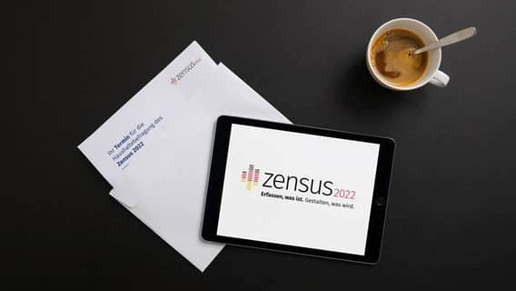 The coffee mug and material for the 2022 census household survey is on a black background.  © Federal and State Statistical Offices 