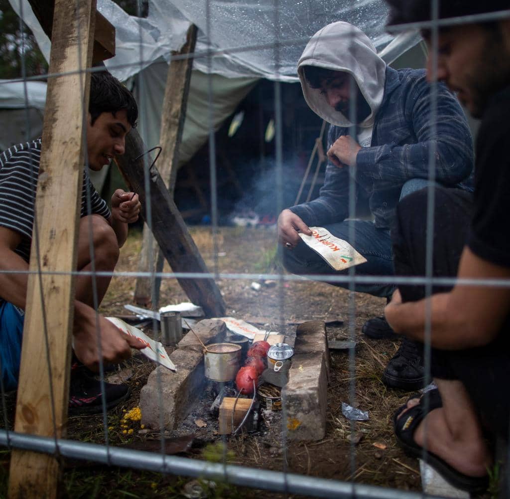 Migrants prepare food at a newly built refugee camp at the Rudninka military training area in Lithuania